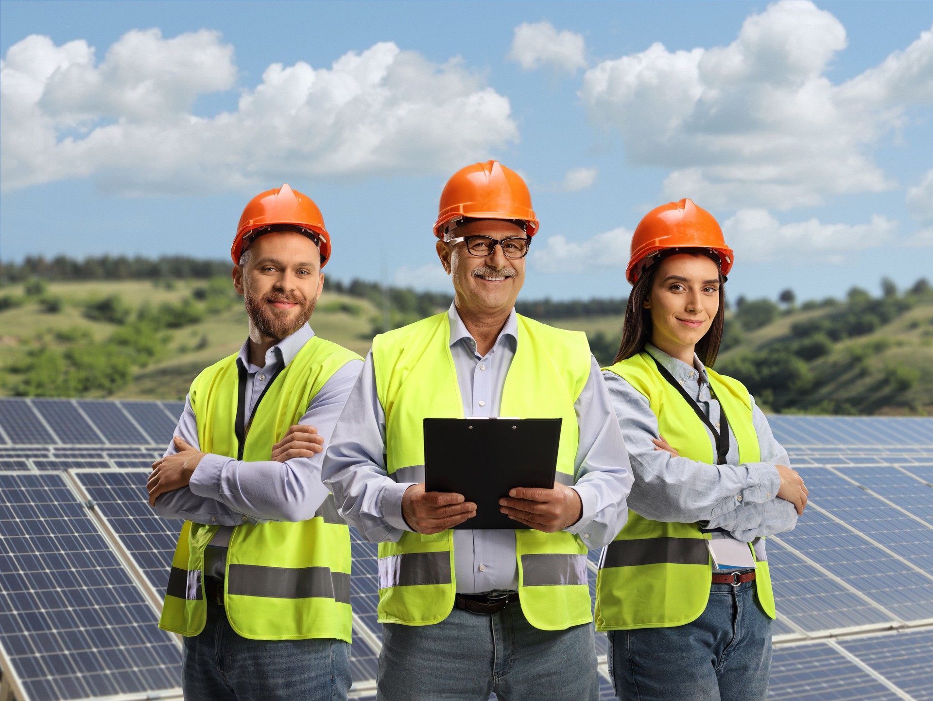 Team of young and mature engineers with safety vests on a solar farm
